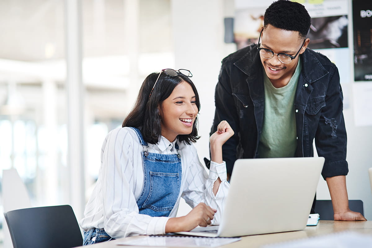 Two people looking at a laptop and smiling
